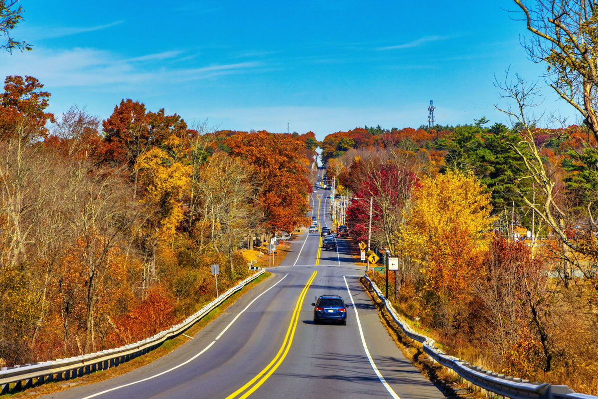 USA, Massachusetts, Scenic Road Through Autumn Foliage with Cars, Colorful Trees, Blue Sky, and New England Fall Landscape