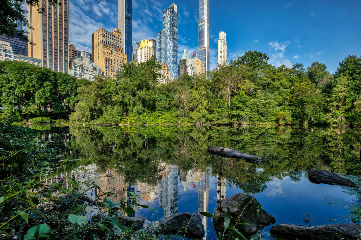 USA, New York City, Manhattan, Central Park, the Pond near Central Park South with Lush Greenery and Reflections of Midtown Skyscrapers, Including the Essex House and Billionaires’ Row, on a Sunny Day – A Beautiful View